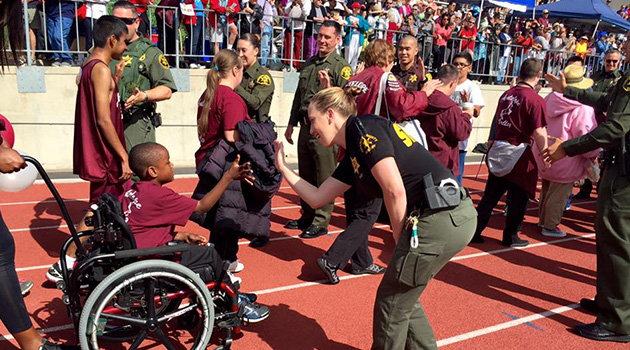 Child in wheelchair giving high-fives to Sheriff's Department officers