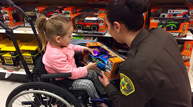 Child in wheelchair selecting a toy with a Sheriff's Department officer