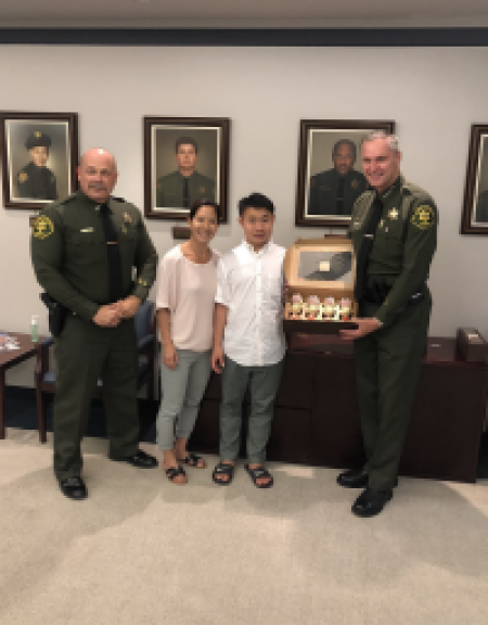 Two officers and two children pose for photo while holding cupcakes